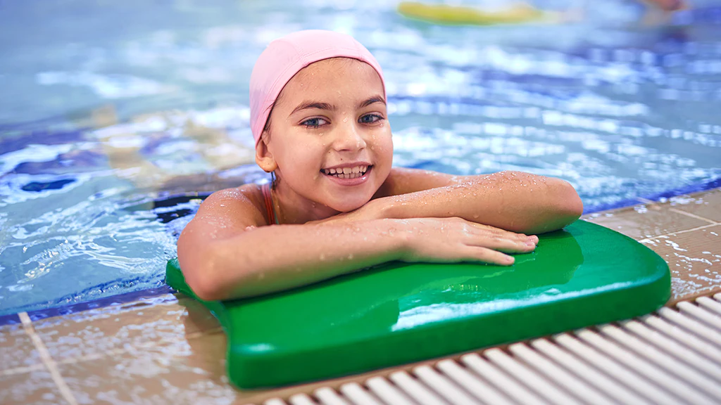 Niña dentro de una piscina moviendo las piernas y con un flotador