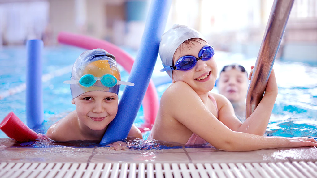 Niñas apoyadas en la escalera de una piscina interior